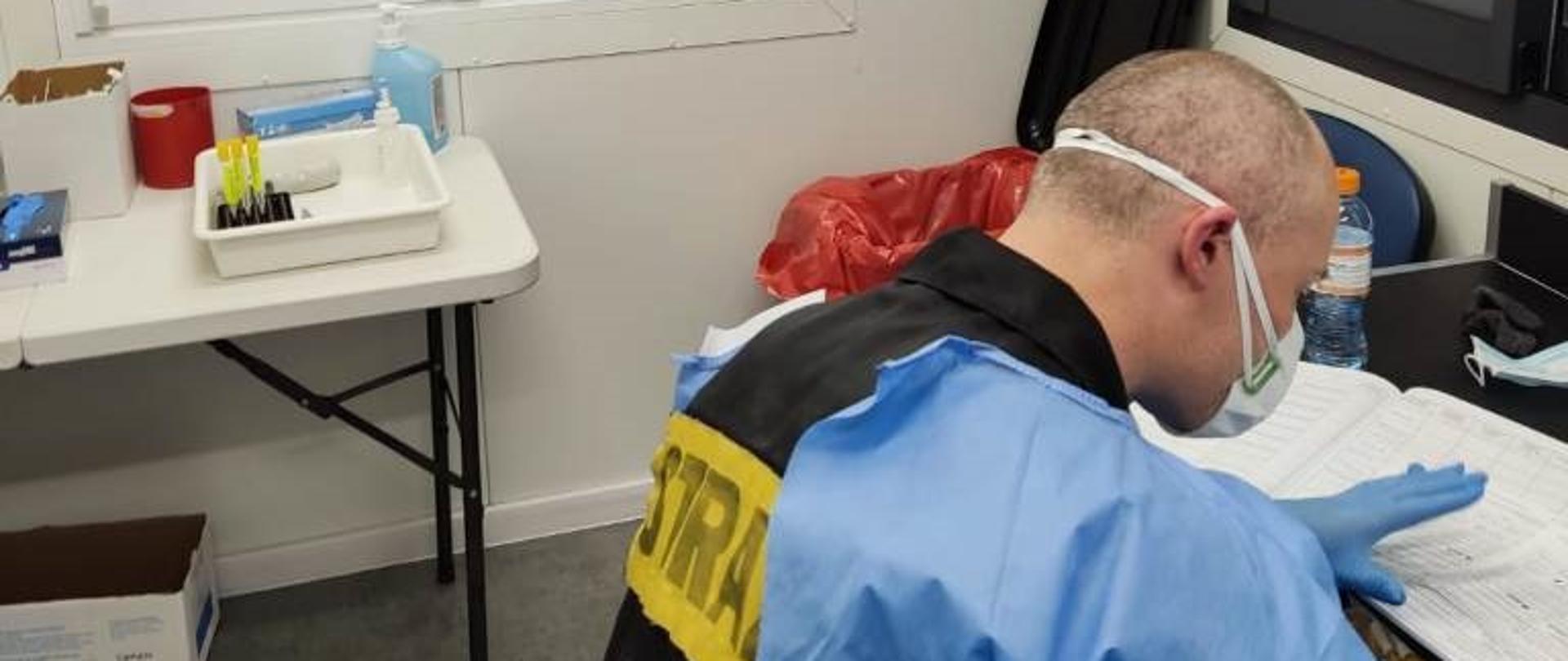 Strażak w ubraniu ochronnym pracuje w punkcie pobrań wymazów na COVID-19.