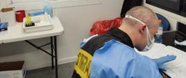 Strażak w ubraniu ochronnym pracuje w punkcie pobrań wymazów na COVID-19.