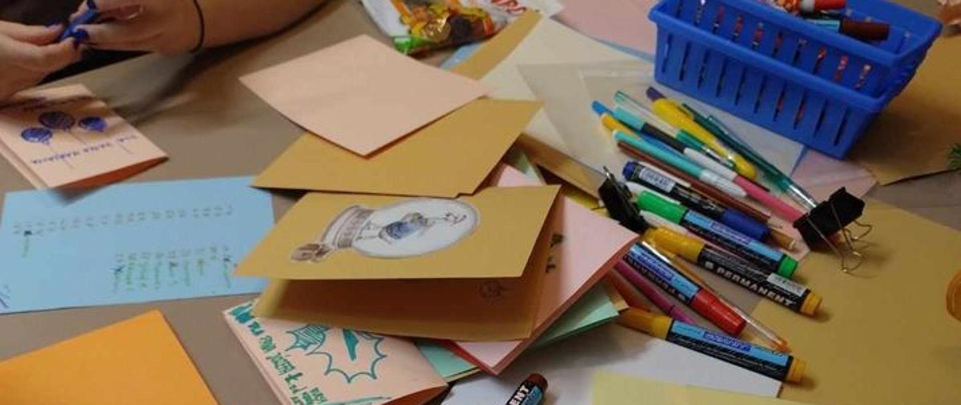 na stole kredki i katony z których przygotowywane są kartki świąteczne