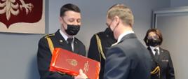 Zdjęcie przedstawia wręczenie przez Komendanta Miejskiego PSP w Białymstoku drobnych upominków okolicznościowych