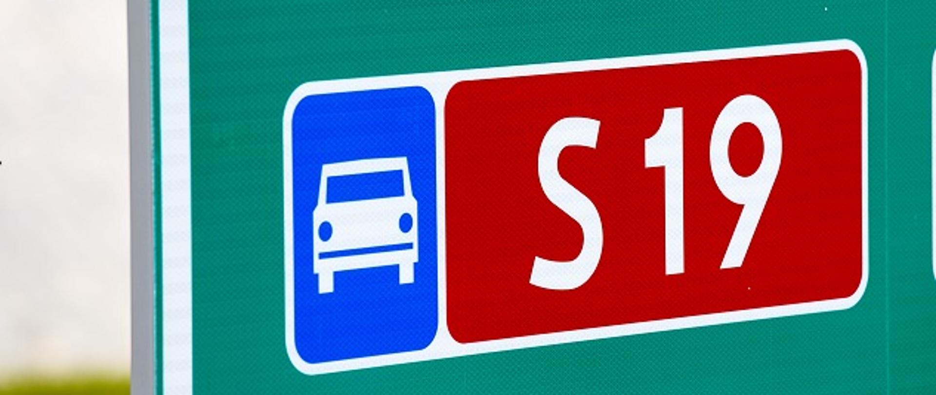 Znak informacyjny, oznaczający drogę ekspresową (białe auto od przodu na niebieskim tle) oraz czerwona tablica oznaczająca numer drogi ekspresowe (literka S i numer 19 na biało) 