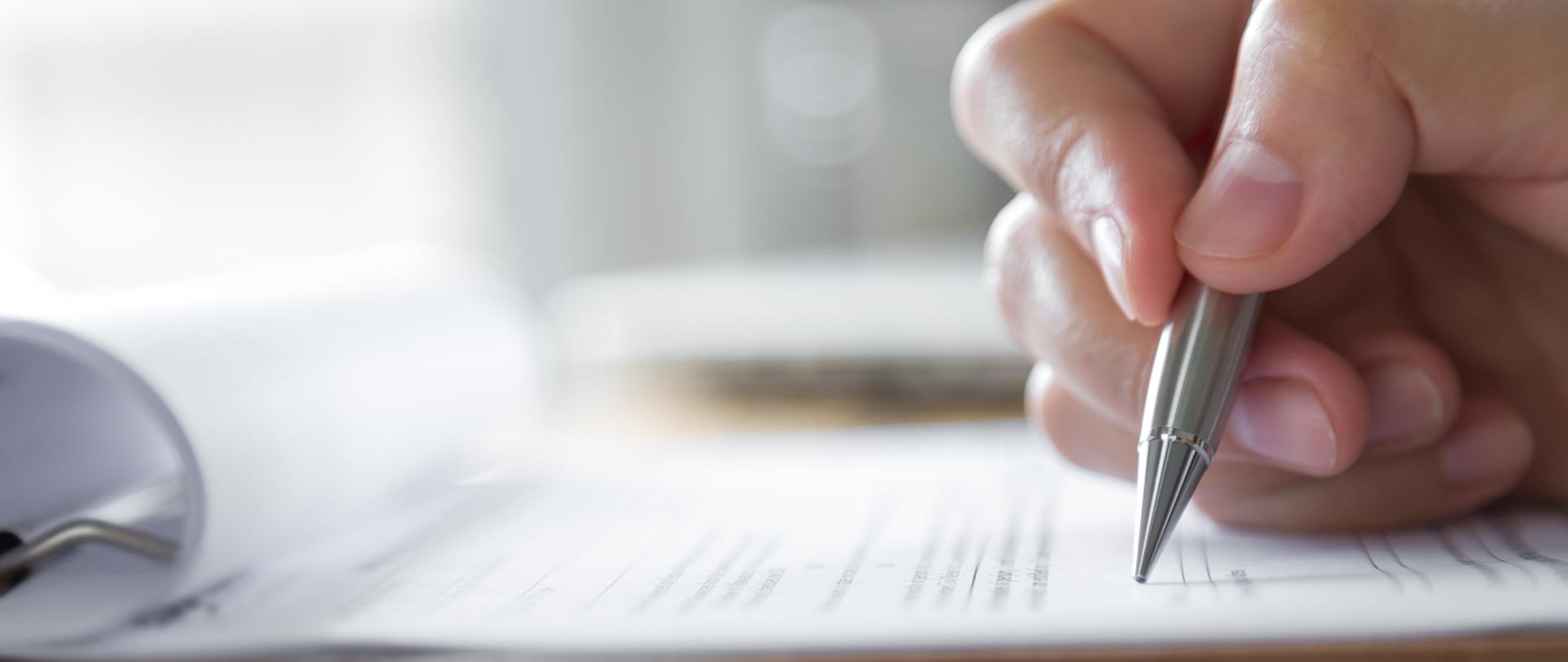 Hand with pen over application form