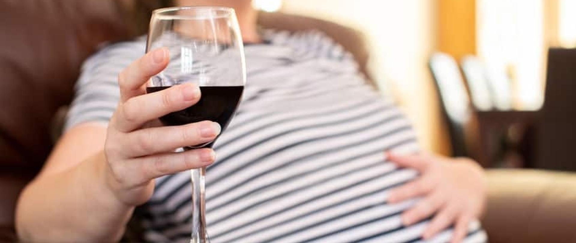 Kobieta w ciąży trzymająca kieliszek z czerwonym winem