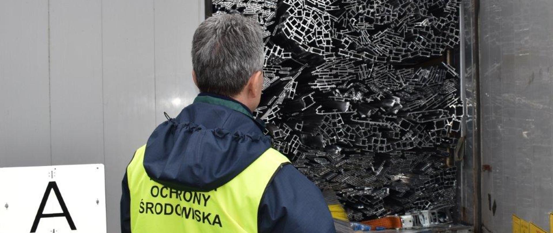 Inspektor Ochrony Środowiska kontrolujący zawartość naczepy ciężarówki.