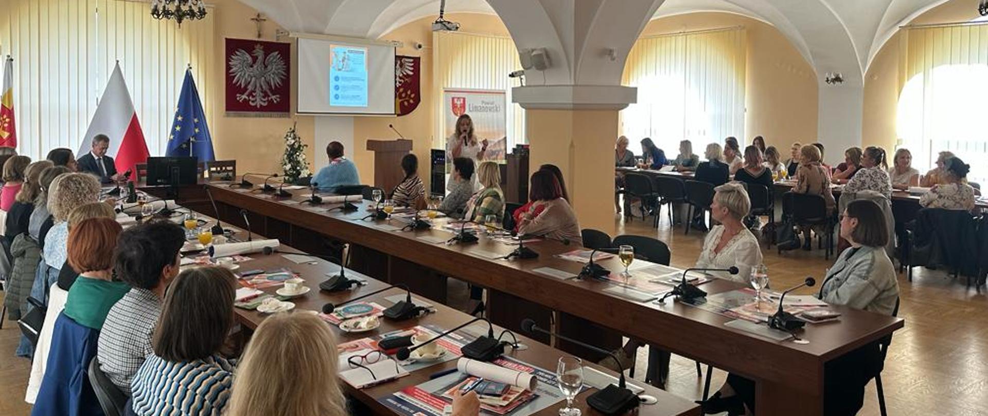 Na zdjęciu widać prelegenta oraz salę wykładową z uczestniczącymi słuchaczami.