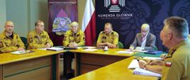 Zastępca komendanta głównego i sześciu oficerów z KG PSP oraz mężczyzna w ubraniu cywilnym siedzący przy stole. 