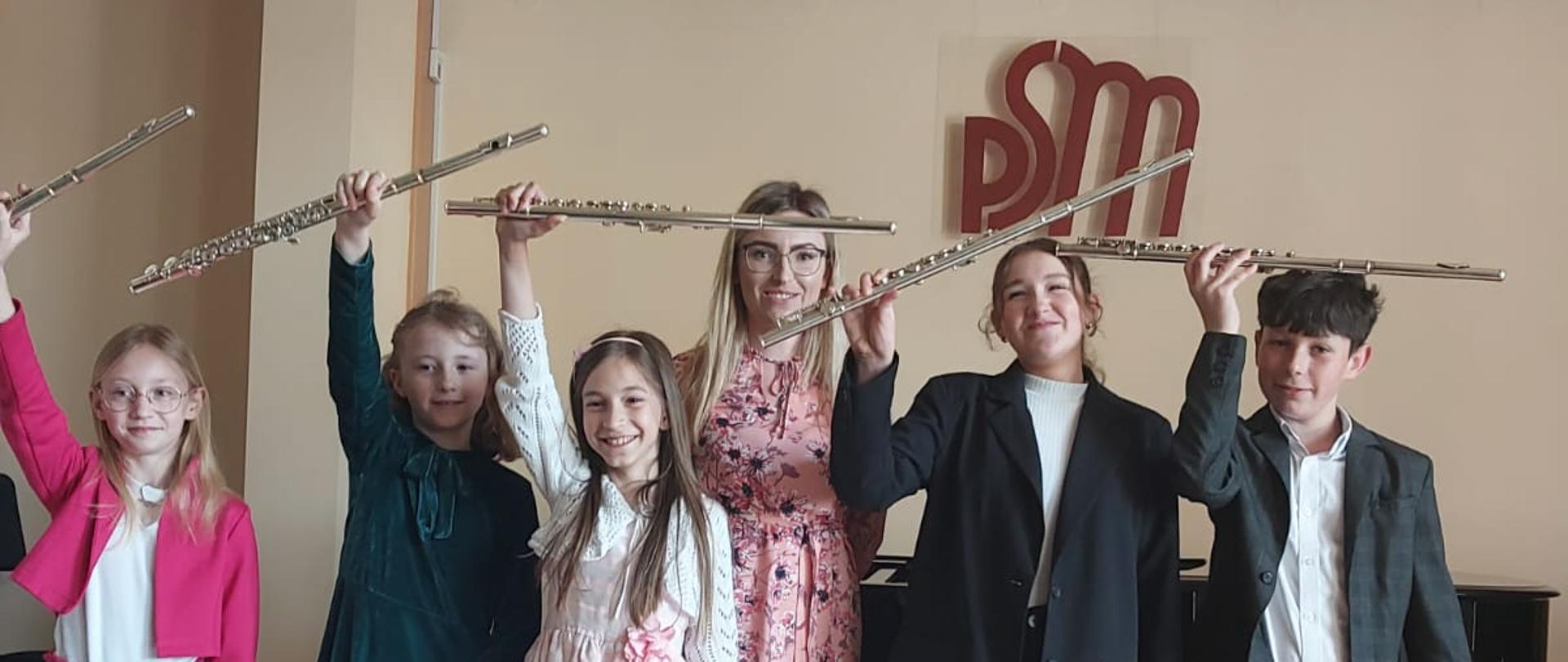 zdjęcie- uczniowie z fletami trzymającymi w górze