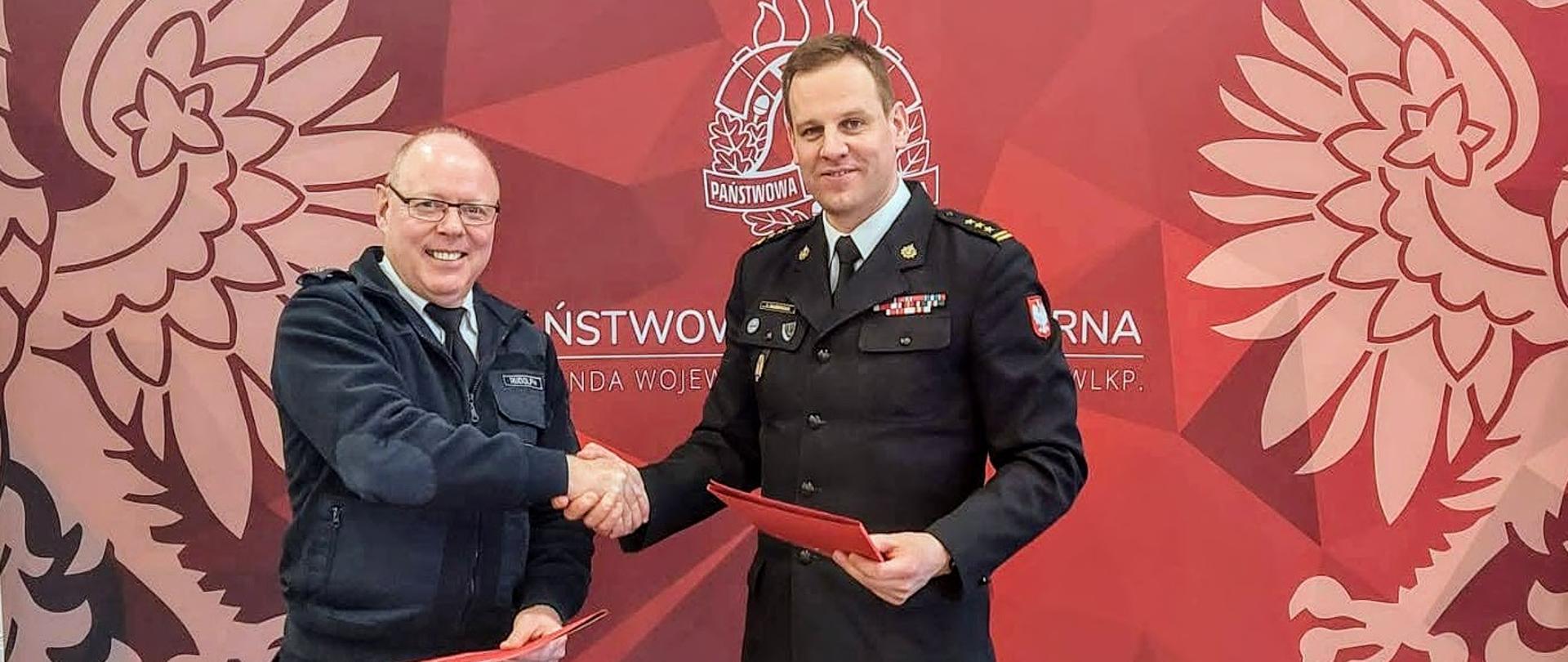 Podpisanie planu współpracy KW PSP w Gorzowie Wlkp. z LSTE w Eisenhüttenstadt na 2023 rok - uścik dłoni Lubuskiego Komendanta Wojewódzkiego oraz Dyrektora szkoły