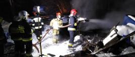 Strażacy dogaszają budynek gospodarczy . Oświetlenie terenu przy pomocy najaśnicy