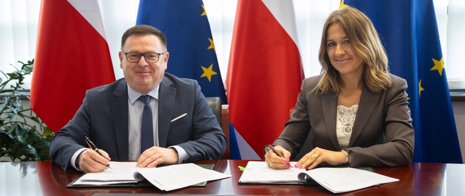 Mężczyzna i kobieta siedzą przy stole i podpisują dokumenty