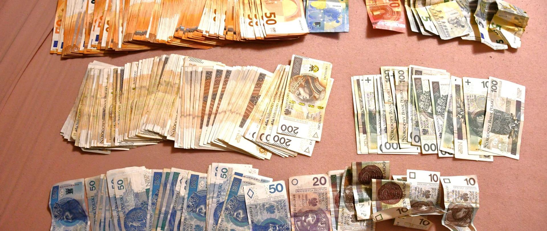 Rozłożone liczne banknoty w kilku nominałach i walutach, ułożone w kilku rzędach.