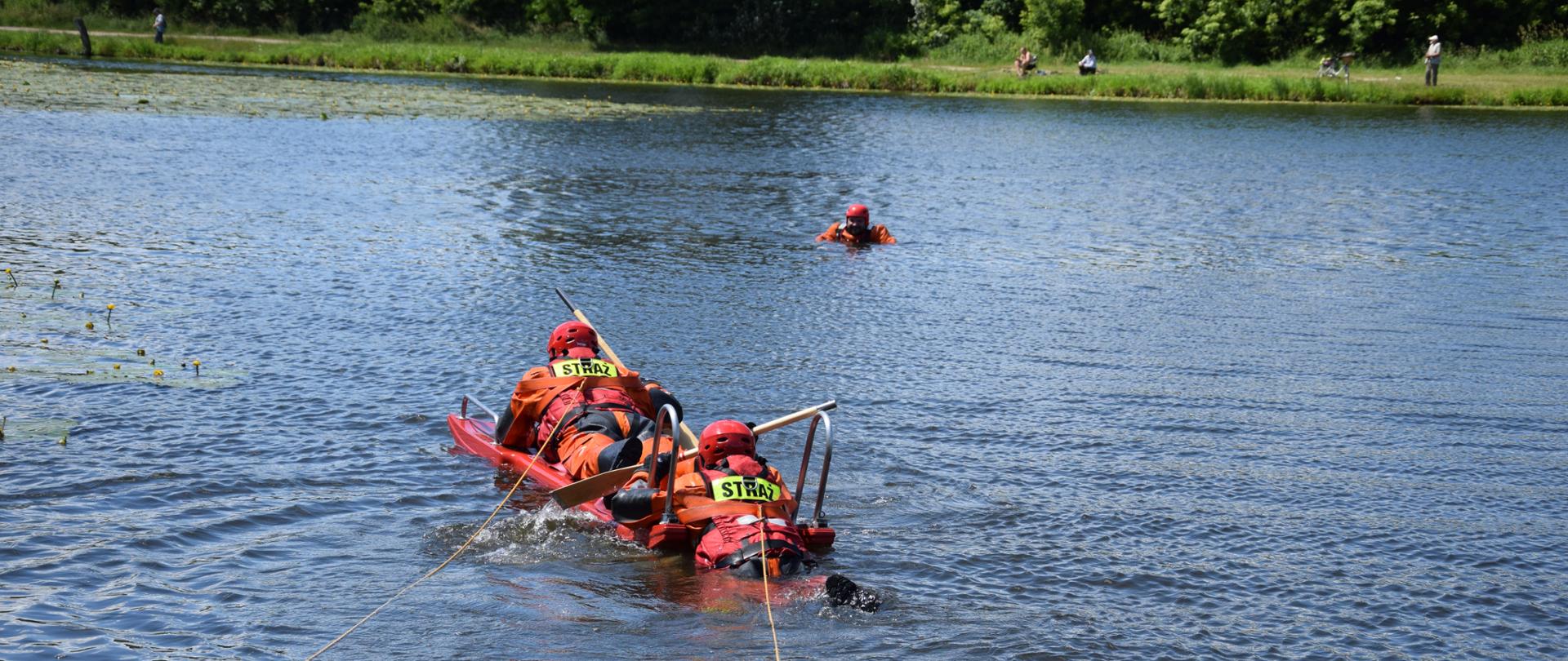 Strażacy na zbiorniku wodnym podczas próby podjęcia z wody pozoranta przy użyciu sani wodno - lodowych