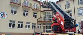 Strażacy z wykorzystaniem drabiny mechanicznej wykonują ewakuację przez okno budynku z 2 piętra.