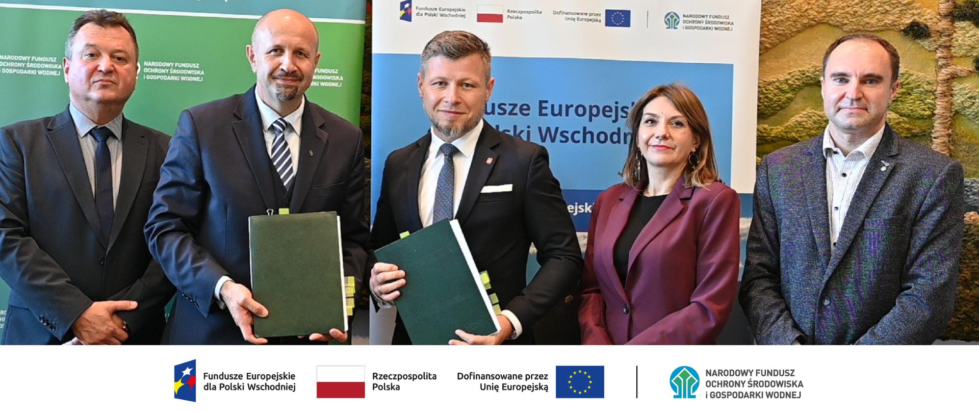 Na zdjęciu od lewej: Robert Markiewicz zastępca dyrektora Departamentu Adaptacji do Zmian Klimatu, Robert Gajda zastepca prezesa zarządu NFOŚiGW , Adam Kostrząb burmistrz Jasła, Anna Wojnarowicz-Więcek kierownik Wydziału Księgowości w Urzędzie Miasta Jasło, Maciej Kilanowski doradca Departament Adaptacji do Zmian Klimatu. Na dole ciąg znaków, logotypy od lewej: FE dla Polski Wschodniej, flaga Rzeczypospolita Polska, flaga UE Dofinansowane przez UE, NFOŚiGW.