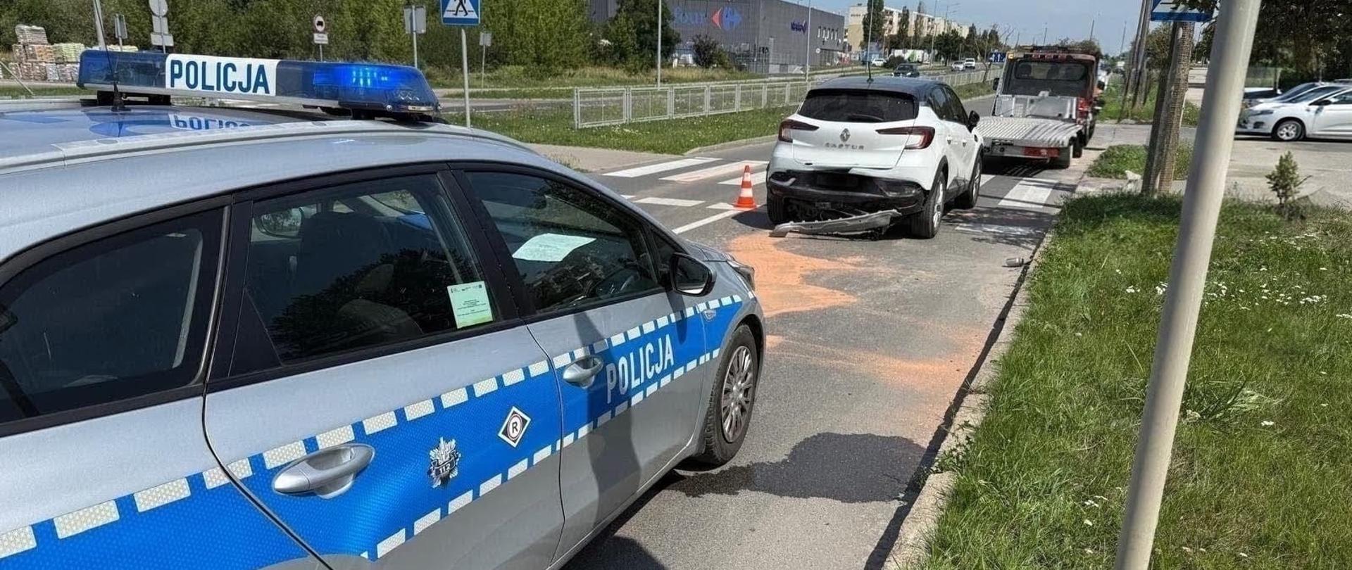 Uszkodzony w zdarzeniu samochód osobowy, patrol Policji oraz autolaweta