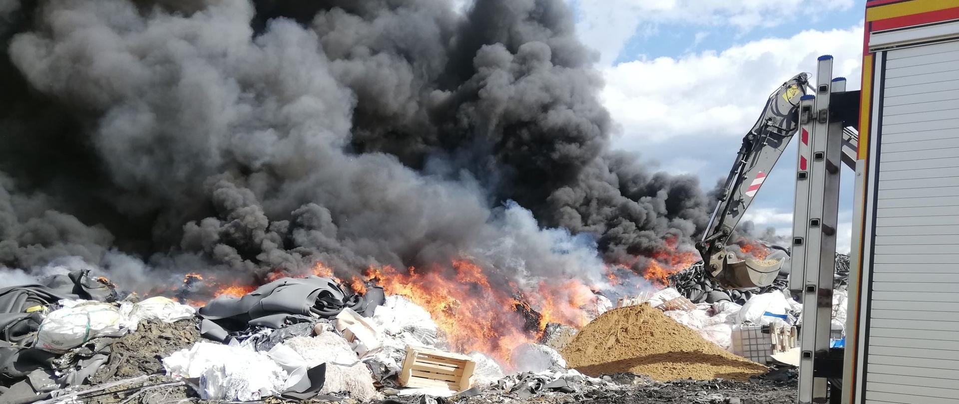 Na zdjęciu palące się składowisko odpadów. Wydziela się gęsty, czarny dym.