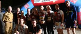 grupa uczestników XIII Biegu Ogniowego pozuje do wspólnego zdjęcia przy bramie wydarzenia.