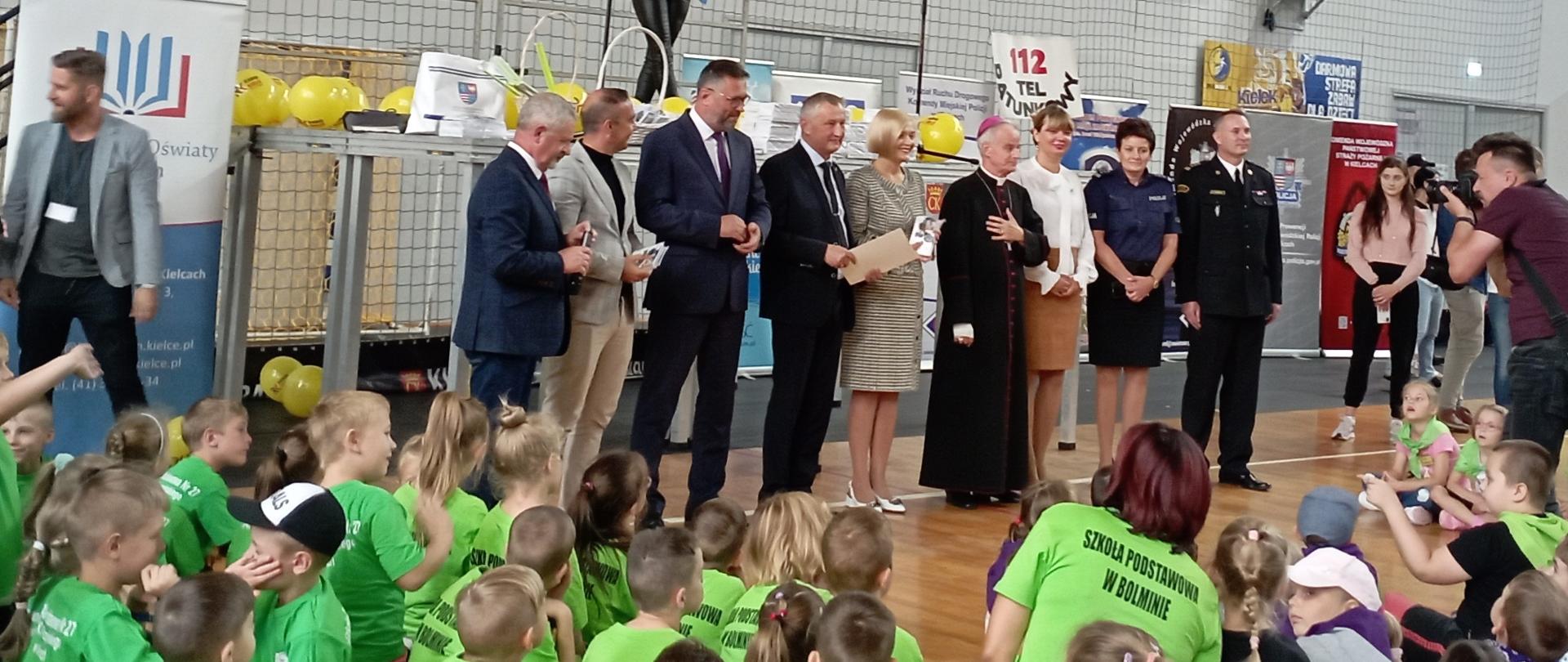 Zdjęcie przedstawia przedstawicieli władz, formacji mundurowych i organizatorów, którzy stoją przed uczestnikami przedsięwzięcia edukacyjno-profilaktycznego .