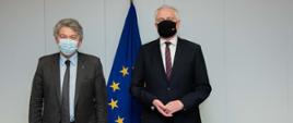 Wicepremier, minister rozwoju, pracy i technologii Jarosław Gowin w maseczce na twarzy, po jego lewej stronie stoi Komisarz ds rynku wewnętrznego Thierry Breton. Z tyłu flagi UE.