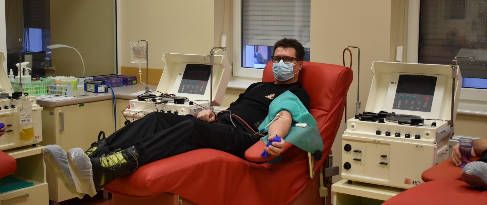 djęcie przedstawia mł. bryg. Jarosława Gryciuka podczas oddawania osocza