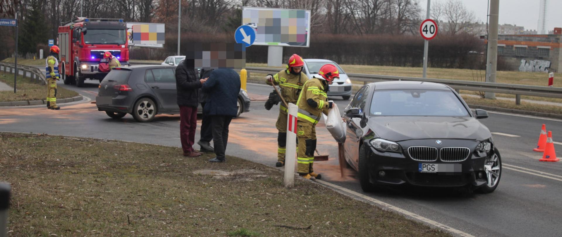 Strażacy wysypują sorbent na rozlany olej.