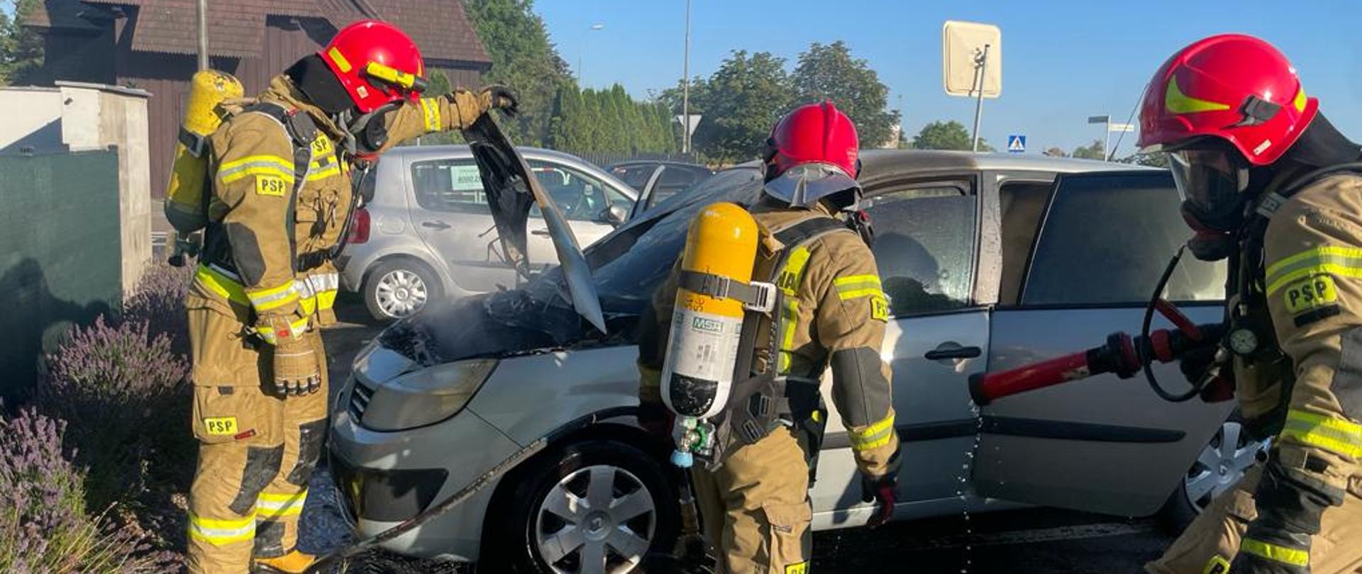Strażacy przy palącym się samochodzie już dogaszony