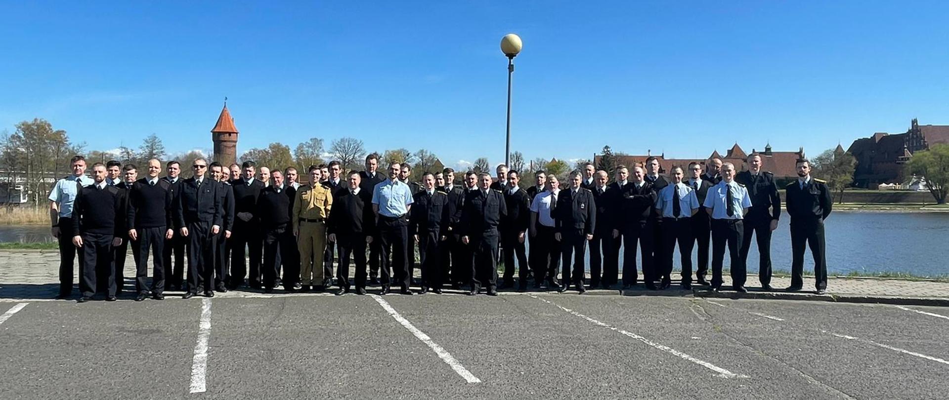 Funkcjonariusze Państwowej Straży Pożarnej stoją obok siebie.