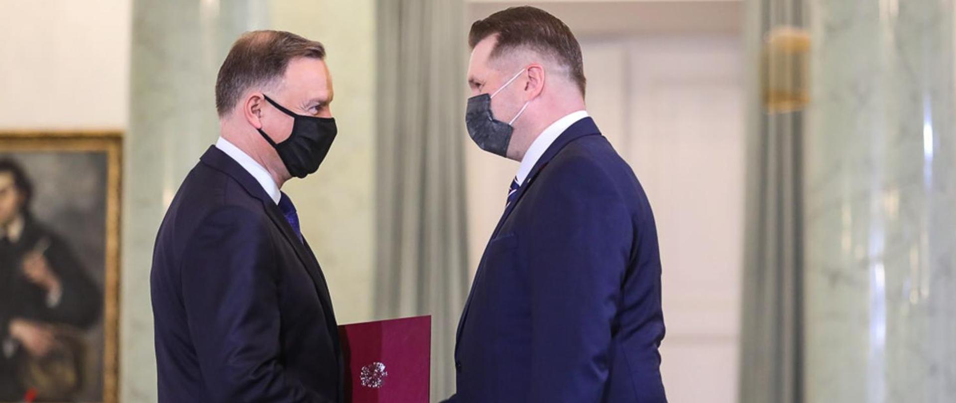 Prezydent i prof. Czarnek w maseczkach podają sobie ręce.