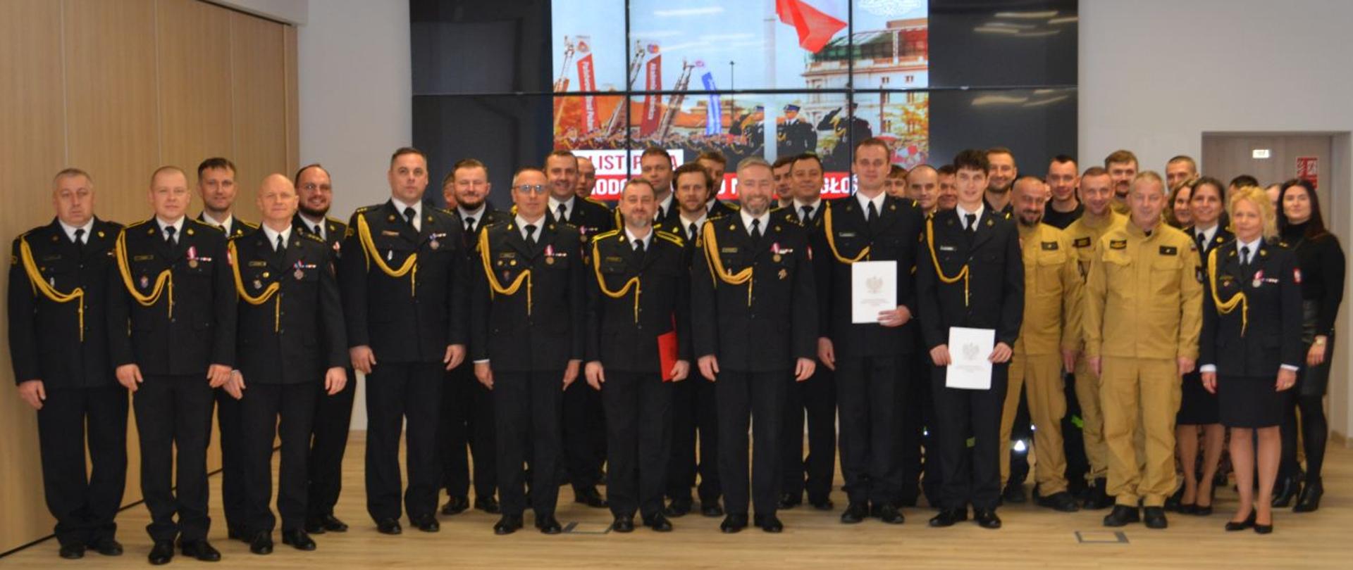 Strażacy otrzymujący wyróżnienia i awanse podczas zbiórki.