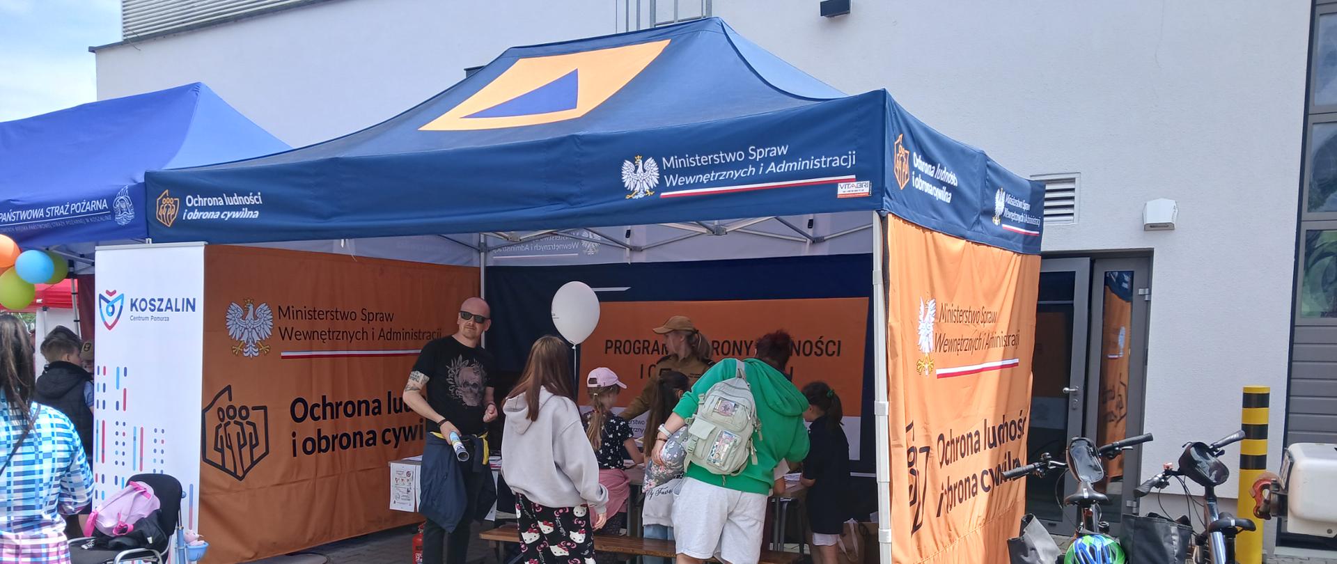 Dzieci i rodzice uczestniczą w zajęciach edukacyjnych prowadzonych w namiocie programu Ochrona Ludności i Obrona Cywilna.