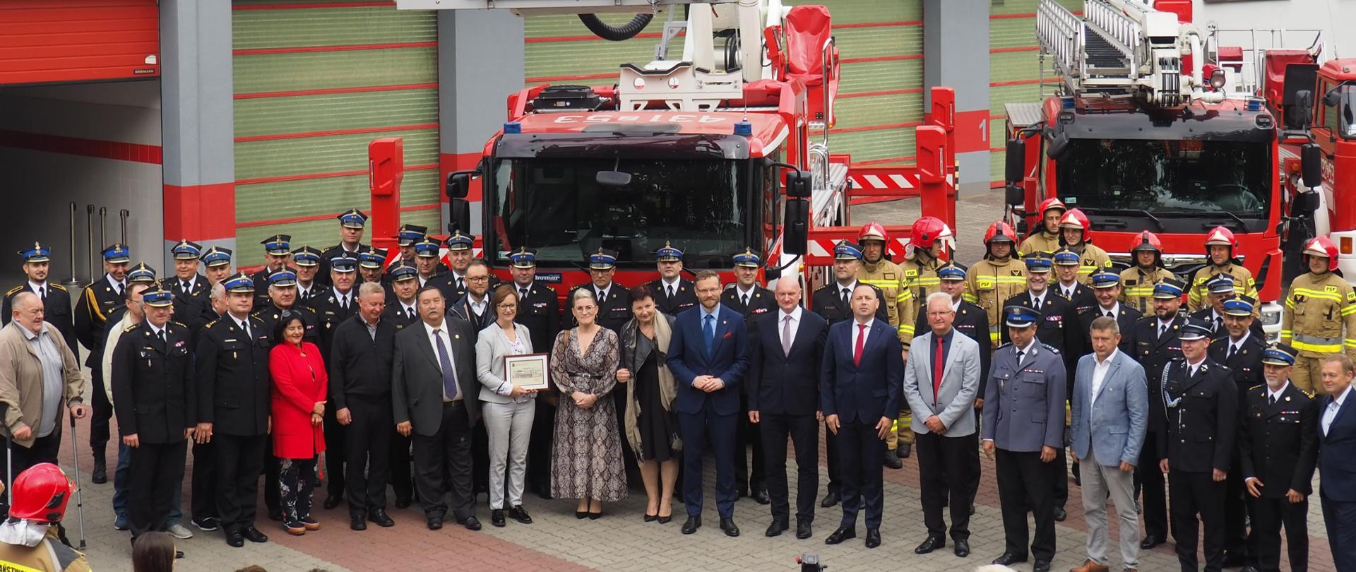Zdjęcie grupowe funkcjonariuszy oraz zaproszonych gości. W tle garaże JRG Goleniów oraz nowy podnośnik.