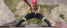 Na zdjęciu znajduje się strażak puszczający się na linie ze wspinalni