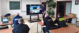 Zdjęcie przedstawia strażaków, policjantów i pracowników zarządzania kryzysowego słuchających wykładu.