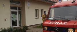 Samochód jednostki Ochotniczej Straży Pożarnej we Wleniu stoi na ulicy przed Przychodnią Rejonową SPZOZ we Wleniu. Na zdjęciu widoczny jest strażak stojący przy samochodzie. 