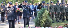 Zdjęcie zrobione podczas uroczystości w intencji pomordowanych żołnierzy w gminie Ciepielów. Na zdjęciu delegacja strażaków oddając honory składa wieniec przed pomnikiem poległych żołnierzy.