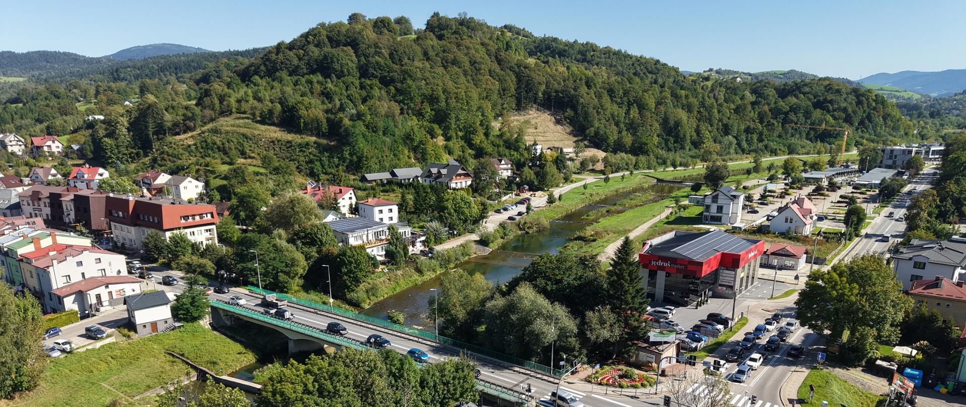 Most w Mszanie Dolnej, widoczna zabudowa miasta, przez centrum płynie Mszanka, w oddali wzniesienia Beskidu Wyspowego, zdjęcie z drona