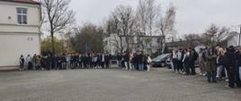 Zdjęcie przedstawia grupę młodzieży wraz z nauczycielami podczas próbnej ewakuacji szkoły - wszyscy stoją na boisku przyszkolnym. Zdjęcie przedstawia ok 120 osób ustawionych w półkolu.