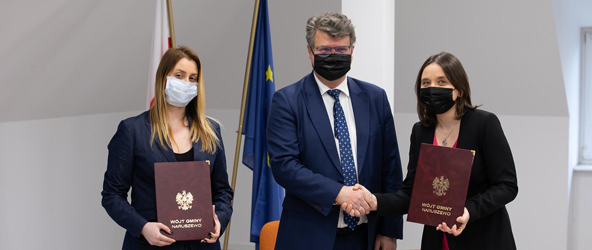 Na zdjęciu widać wiceministra Macieja Wąsika pozującego do zdjęcia z przedstawicielami stron podpisujących umowę.