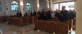 Strażacy oraz goście stojący w ławkach kościelnych 