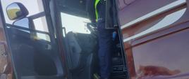 Policjant sprawdzający wnętrze zniszczonej kabiny pojazdu ciężarowego.