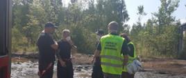 Inspektorzy Ochrony Środowiska wraz z Funkcjonariuszami Państwowej Straży Pożarnej omawiają sytuację na miejscu