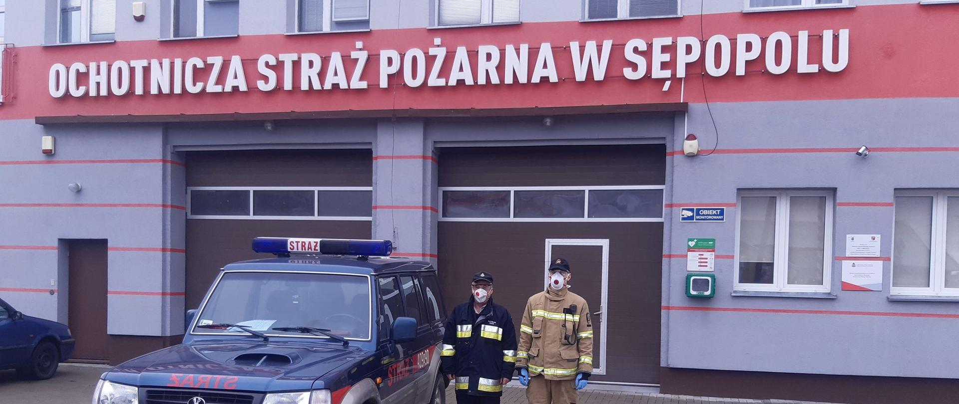 Na zdjęciu widać samochód i dwóch strażaków z Ochotniczej Straży Pożarnej w Sępopolu przygotowanych do transportu osób na szczepienia