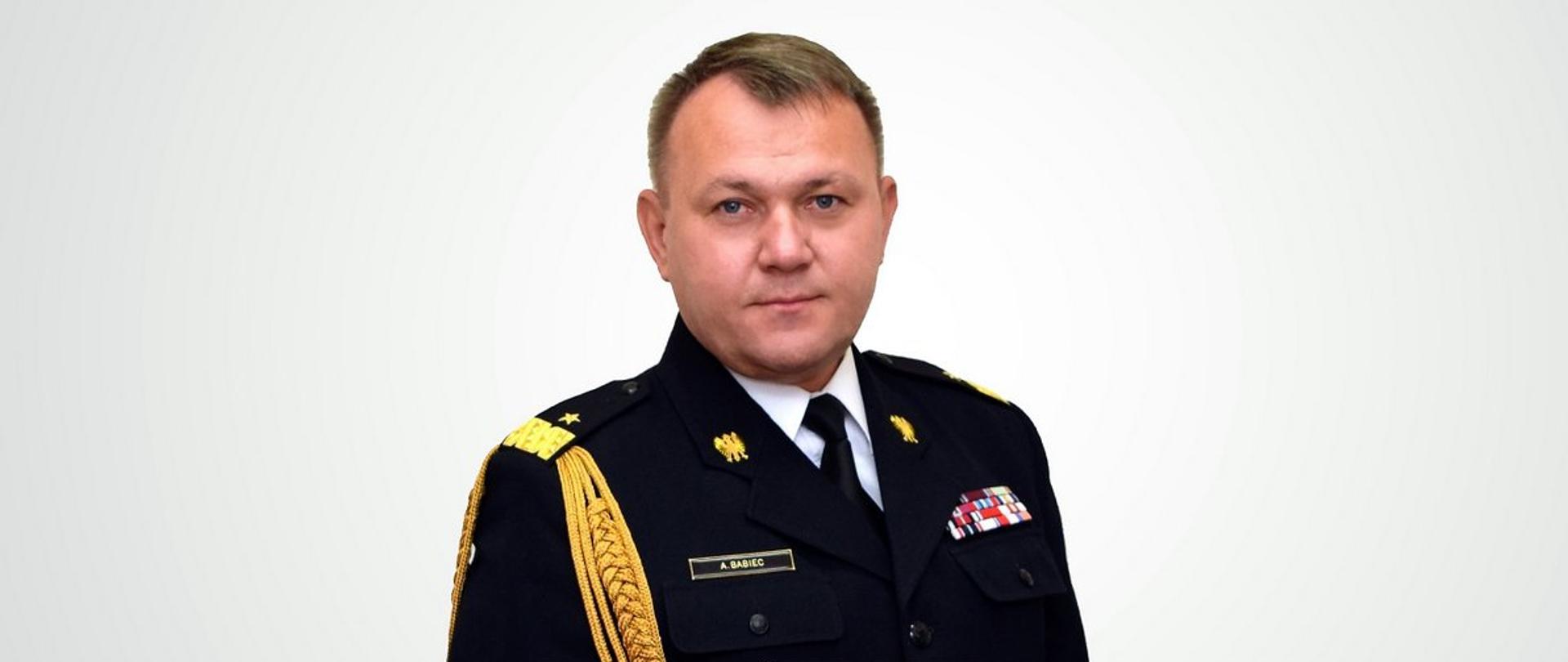 Na szarym tle zdjęcie portretowe Podkarpackiego Komendanta Wojewódzkiego PSP nadbrygadiera Andrzeja Babca w mundurze galowym