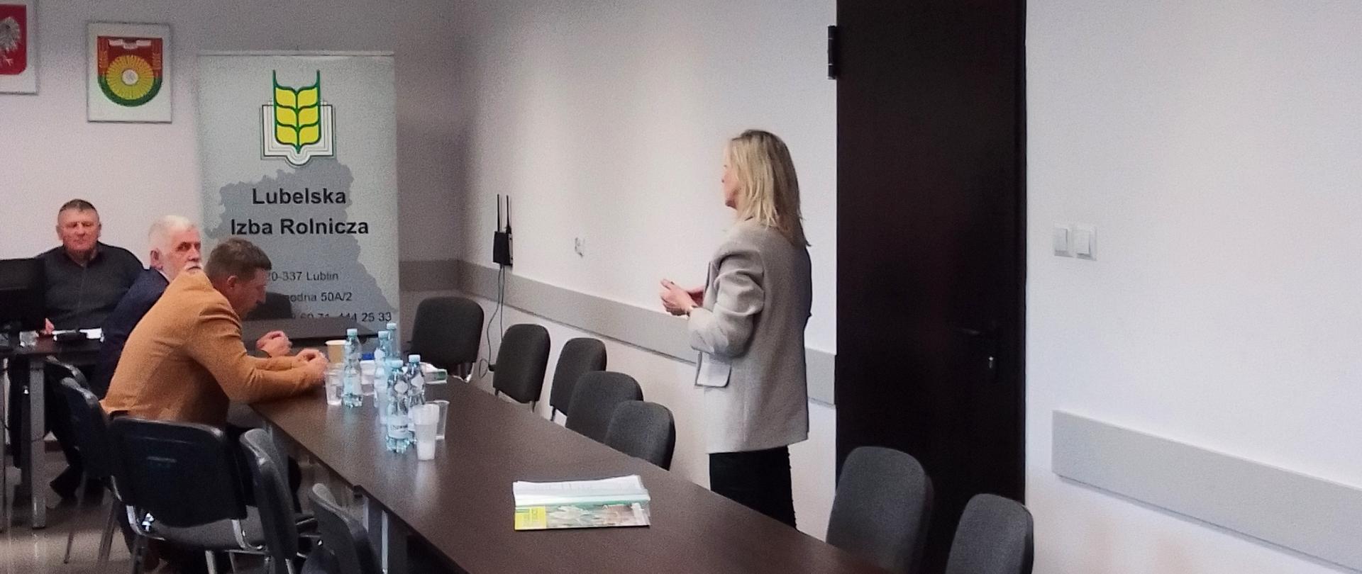 Posiedzenie Rady Powiatowej Lubelskiej Izby Rolniczej powiatu hrubieszowskiego. Trzech mężczyzn i kobieta rozmawiają. W tle rolap Lubelskiej Izby Rolniczej.
