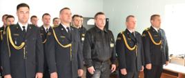 W świetlicy Komendy strażacy w umundurowaniu galowym i koszarowym stoją w pozycji zasadniczej w trzech szeregach