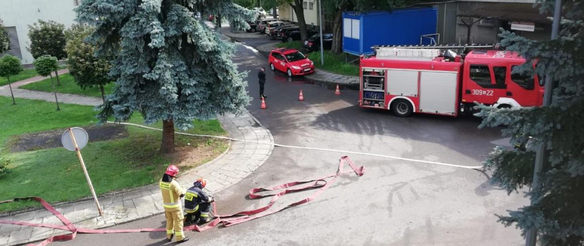 Na zdjęciu widoczni są strażacy przygotowujący sprzęt do ćwiczeń. 