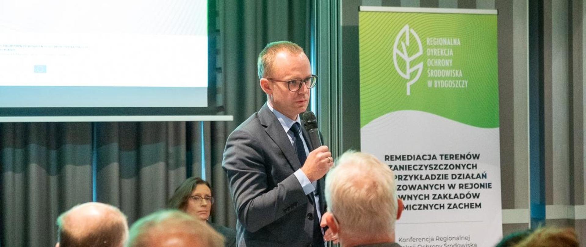Dyrektor RDOS w Bydgoszczy trzyma mikrofon i odpowiada na pytania z sali