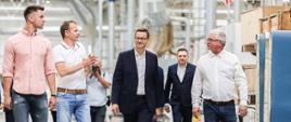 Premier Mateusz Morawiecki idzie z mężczyznami po siedzibie firmy.