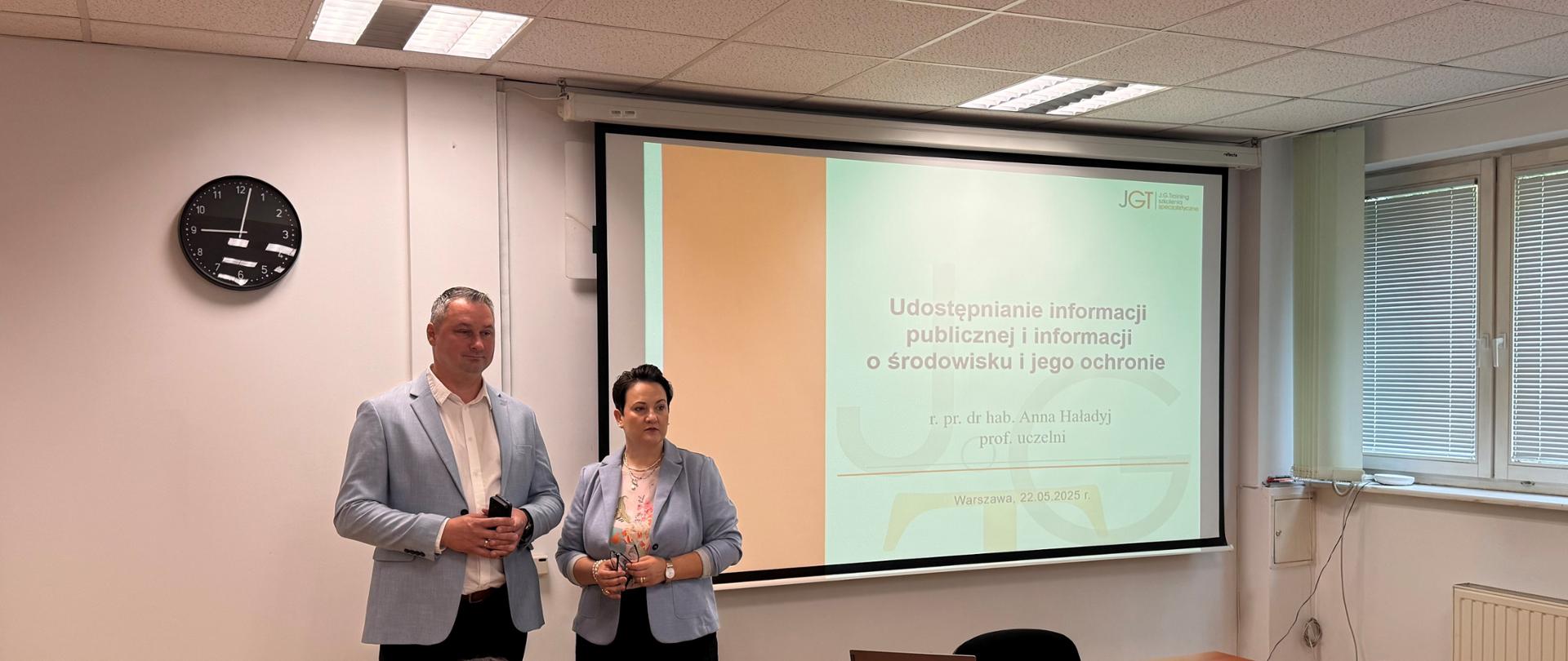 p. Krzysztof Cząstkiewicz, Mazowiecki Wojewódzki Inspektor Ochrony Środowiska oraz p. radca prawny dr hab. Anna Haładyj pozują do pamiątkowego zdjęcia. W tle widać slajd tytułowy szkolenia: „Udostępnianie informacji publicznej i informacji o środowisku i jego ochronie”.