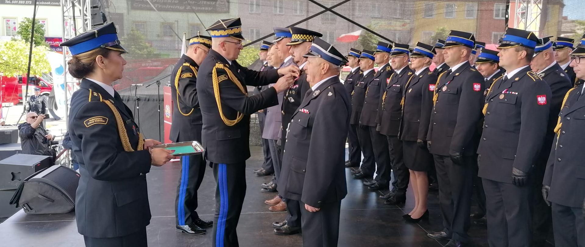 Z-ca komendanta głównego PSP wręcza odznaczenia strażakom stojacym w szeregach